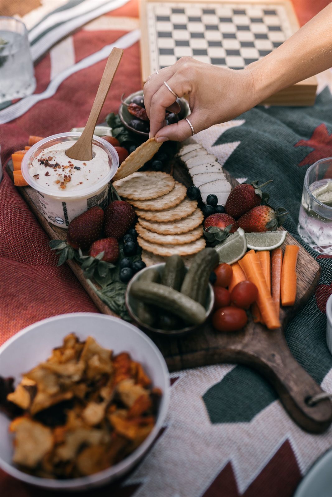 A charcuterie board with a chessboard in the background, evoking the vibe of Carmel Valley Chess Club's women's chess night