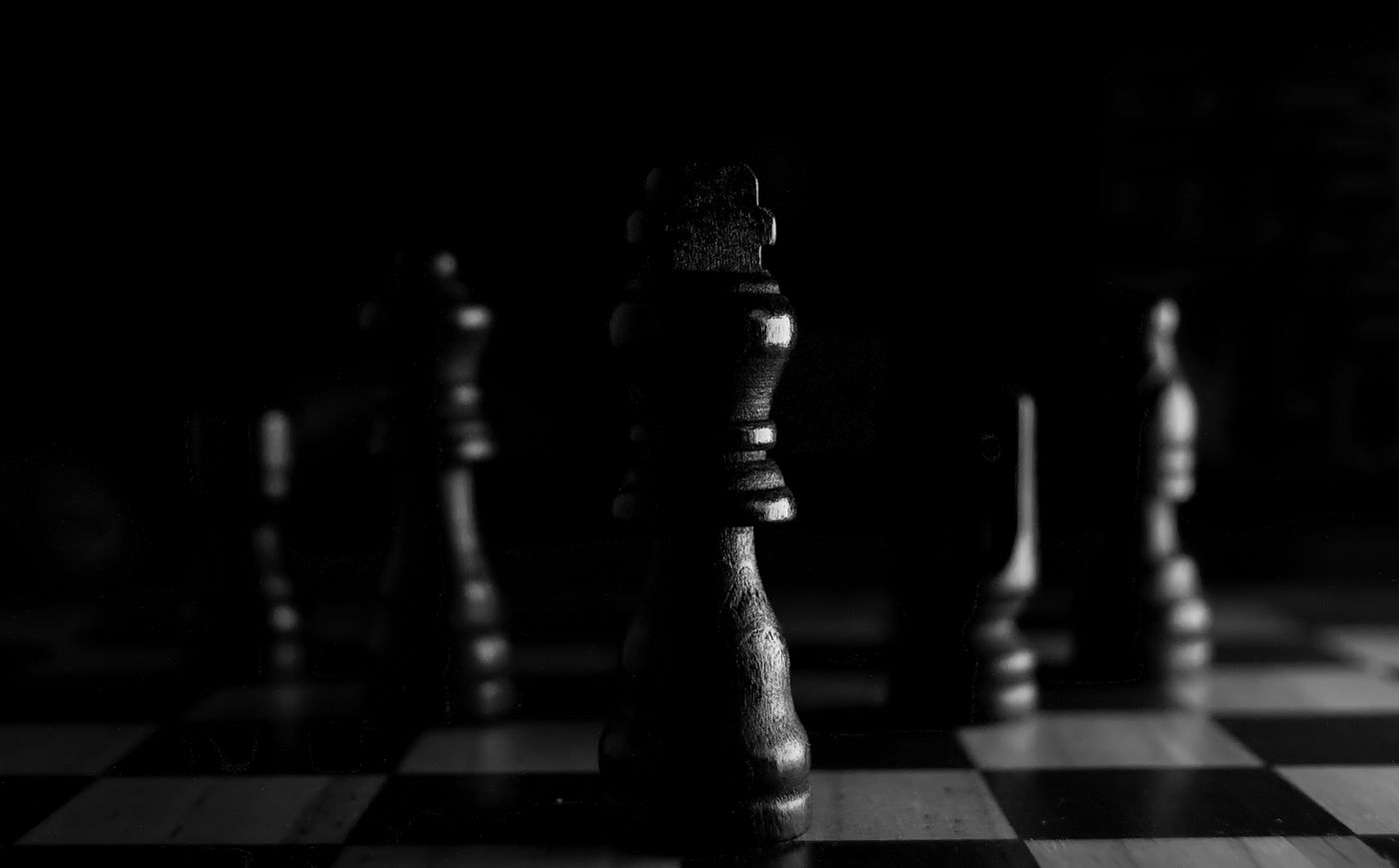 Close-up of chess pieces on a board under dramatic lighting