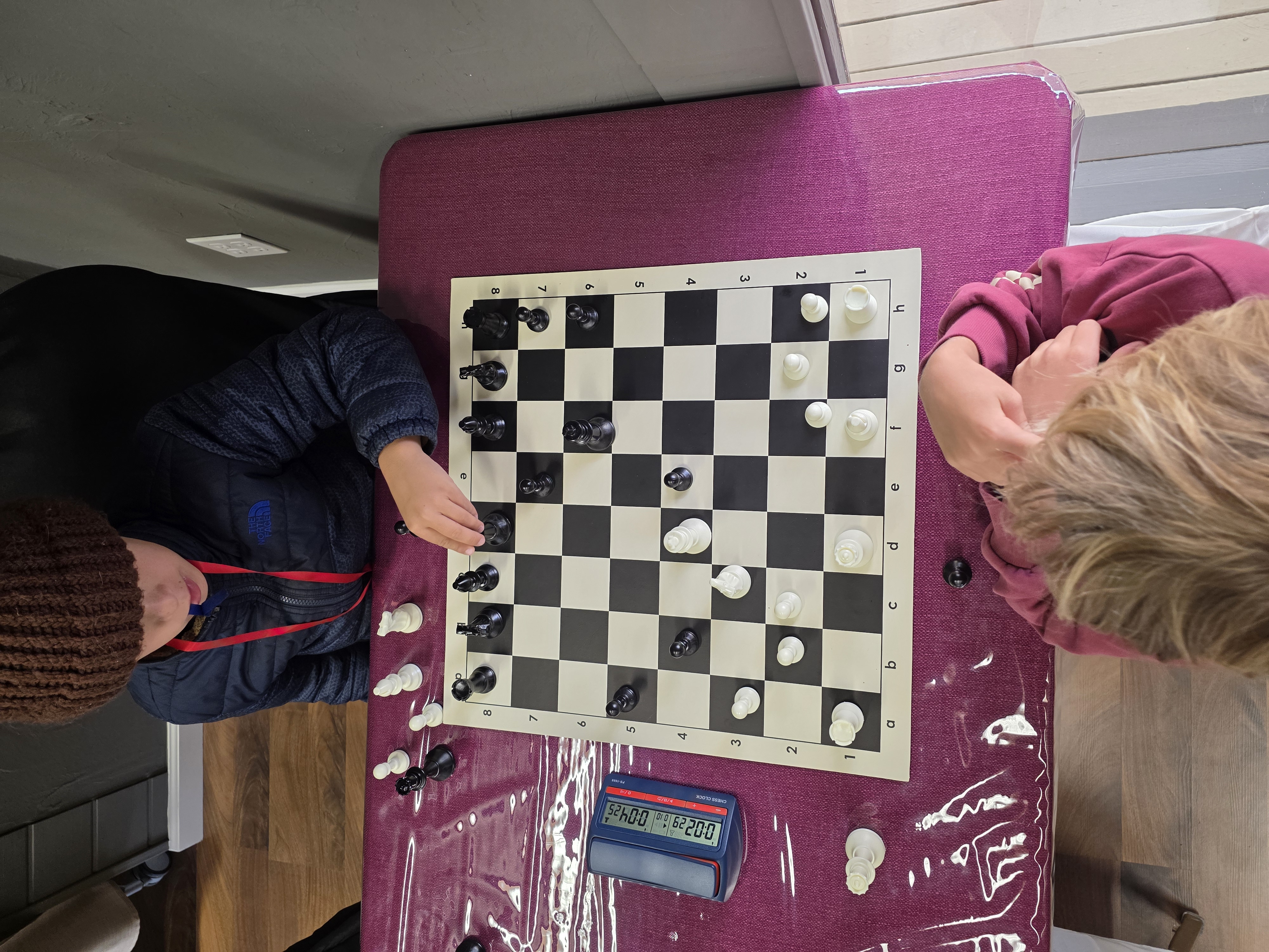Children focused on chess board with chess clock